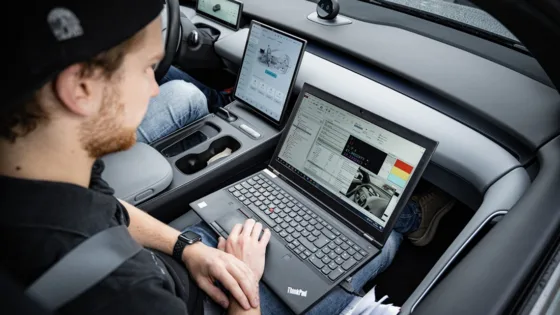 Testingenieur des IFM kalibriert die Messtechnik im Testfahrzeug am Laptop für den ADAS-Benchmark.