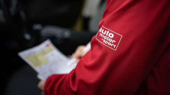 Logo der Zeitschrift auto motor und sport auf der Jacke eines Projektmitglieds der gemeinsamen ADAS-Testreihe von MdynamiX, auto motor und sport und dem IFM. In der Hand hält die Person eine Checkliste zur Vorbereitung der bevorstehenden Testfahrt.