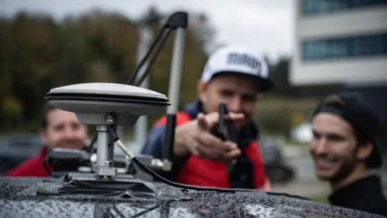 Testfahrer vor einer Testfahrt im Rahmen des ADAS-Benchmark mit Auto motor und sport, dem IFM und der MdynamiX. Im Vordergrund erkennt man eine D-GPS-Antenne auf dem Dach des Fahrzeugs.