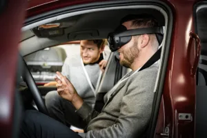 Proband testet automatisierte Fahrfunktionen mit VR-Headset im Fahrzeug zur Analyse von Motion Sickness und Nutzerakzeptanz bei ADAS-Entwicklung.