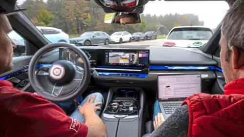 Testfahrer von auto motor und sport während eines Parkassistenztests im Fahrzeug, während das System automatisch in eine Parklücke manövriert und Messdaten aufgezeichnet werden.