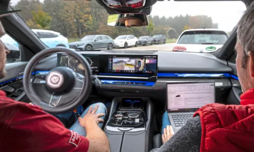 Testfahrer von automotorundsport während eines Tests von Parkassistenzsystemen im Fahrzeug, während das System automatisch in eine Parklücke manövriert und Messdaten aufgezeichnet werden.