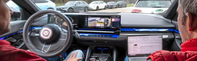 Testfahrer von automotorundsport während eines Tests von Parkassistenzsystemen im Fahrzeug, während das System automatisch in eine Parklücke manövriert und Messdaten aufgezeichnet werden.