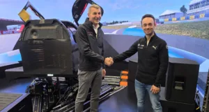 Vertreter von MdynamiX und BMW M Motorsport besiegeln ihre technische Partnerschaft für virtuelle Fahrerlebnisentwicklung per Handschlag vor einem High-End-Fahrsimulator. Im Fokus stehen hochpräzise Lenksystemsimulation, Force-Feedback-Technologie und realistische Fahrerlebnisentwicklung im Motorsport.
